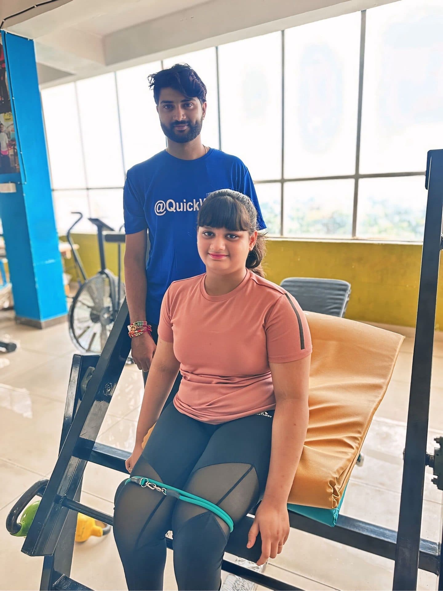 A Quick Walk physiotherapist with a young patient during a session at the exercise rail